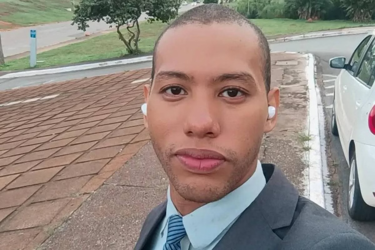 Izaías Godinho sério, de roupa social e fones de ouvido sem fio branco