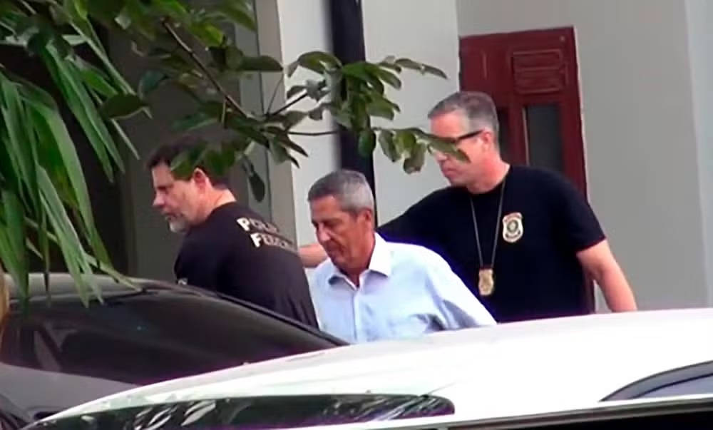 general Walter Braga Netto cabisbaixo, acompanhado de agentes