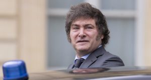 Javier Milei perto de carro, com expressão séria, sem olhar para a câmera