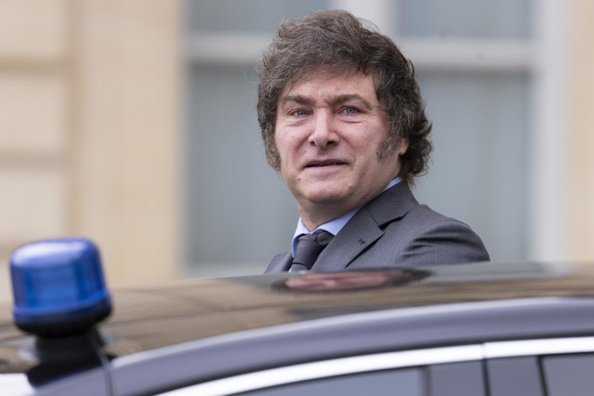 Javier Milei perto de carro, com expressão séria, sem olhar para a câmera