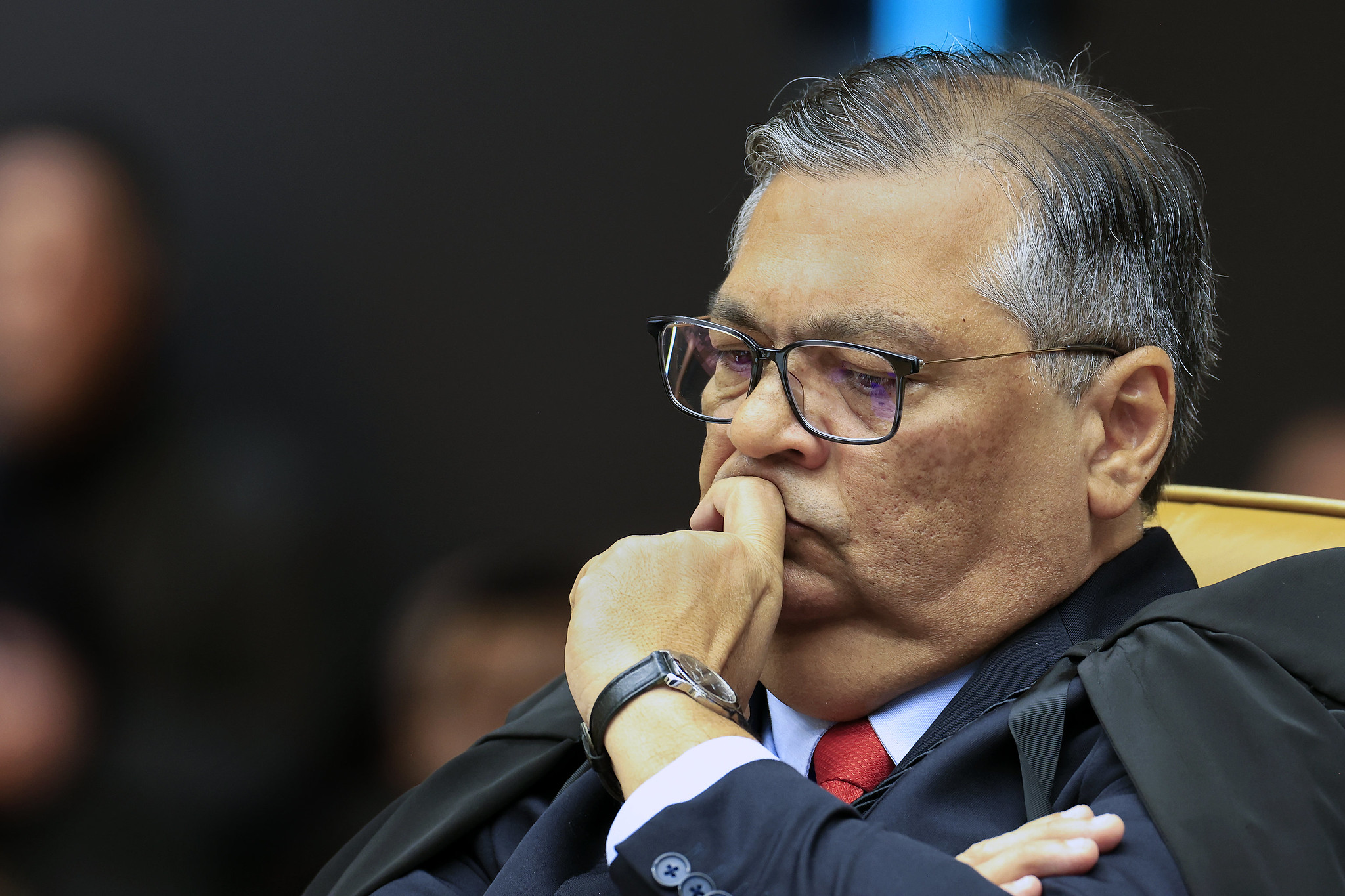 ministro do Supremo Tribunal Federal (STF), Flávio Dino com expressão pensativa, óculos e mão no rosto
