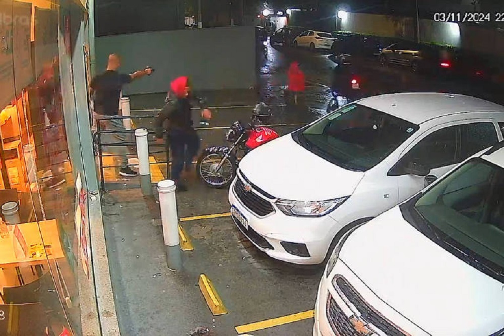 Policial (de preto, na porta do mercado) atirando em Gabriel Renan da Silva Soares (de capuz vermelho)
