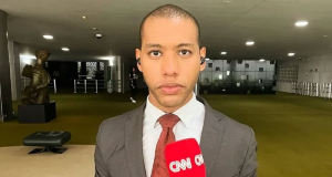 O repórter Izaías Godinho sério, segurando microfone da CNN e olhando pra frente