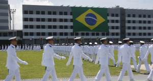 Marinheiros marchando com bandeira do Brasil em prédio ao fundo