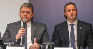 O governador Tarcísio de Freitas (Republicanos) e o secretário da Segurança Pública Guilherme Derrite lado a lado, sentados, o primeiro falando e o segundo sério