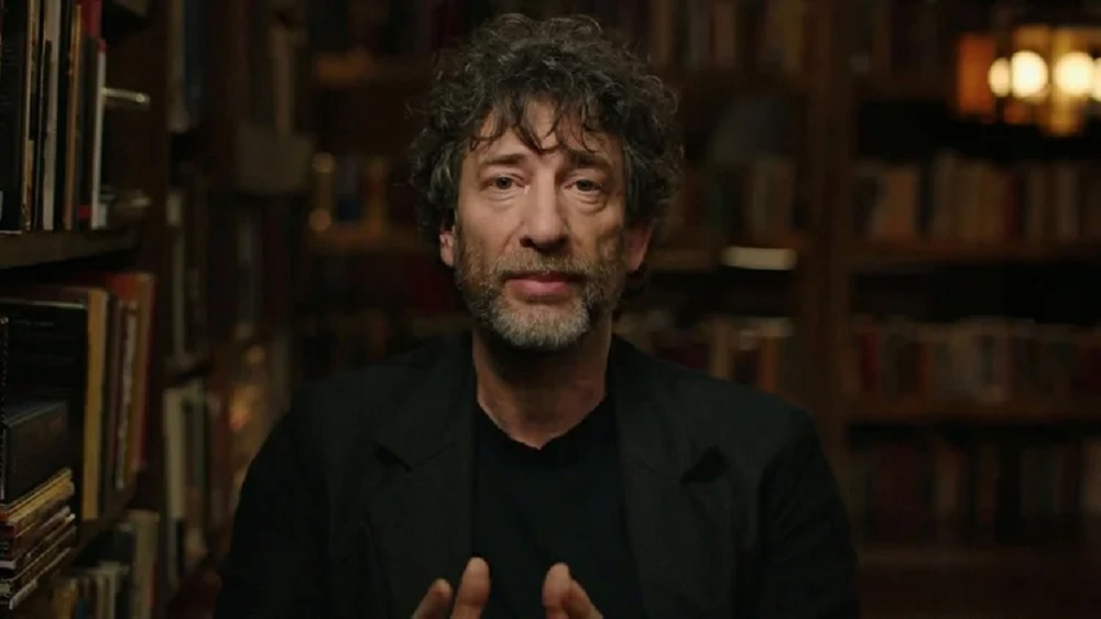 autor britânico Neil Gaiman falando para a câmera, de roupa preta, sério