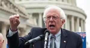 O senador Bernie Sanders falando e gesticulando, sério