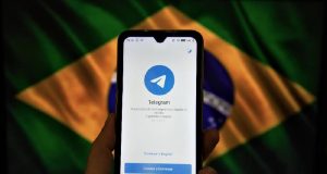 Celular com logo do Telegram e bandeira do Brasil ao fundo
