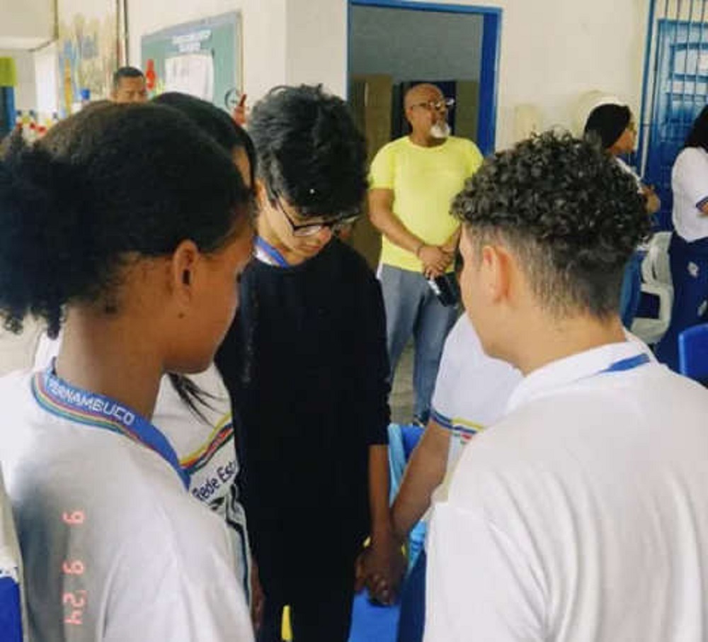 Adolescentes de mãos dadas, olhos fechados e cabeças baixas