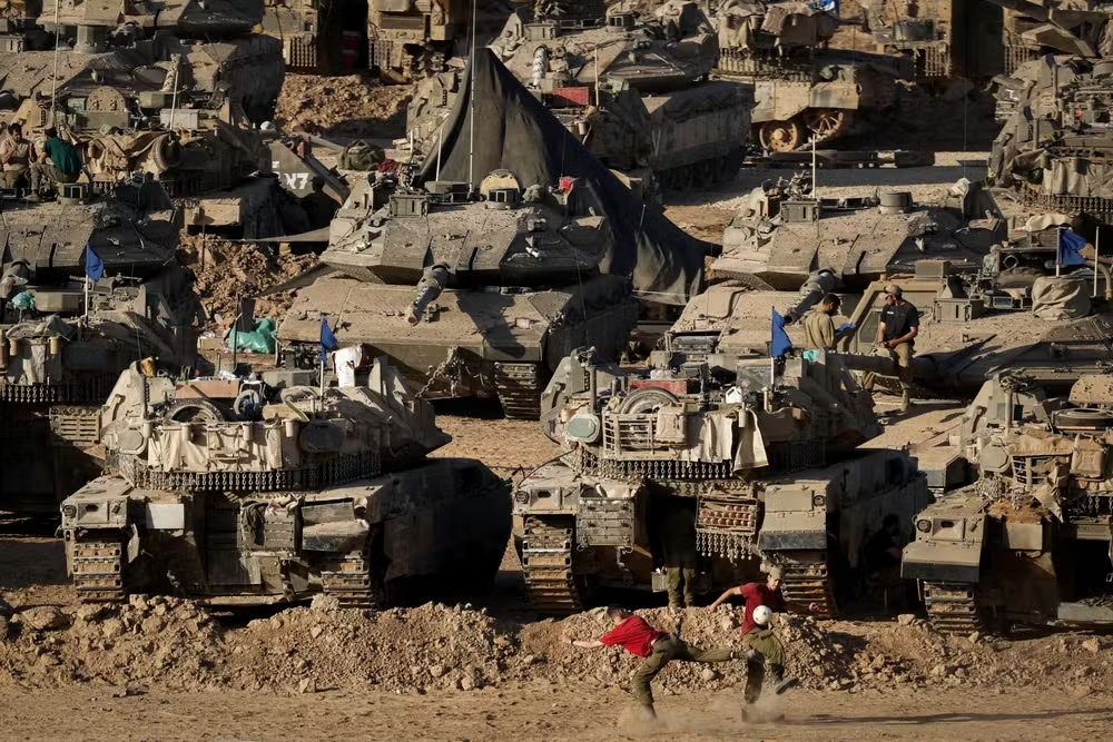 Soldados israelenses jogando futebol diante de tanques e veículos blindados