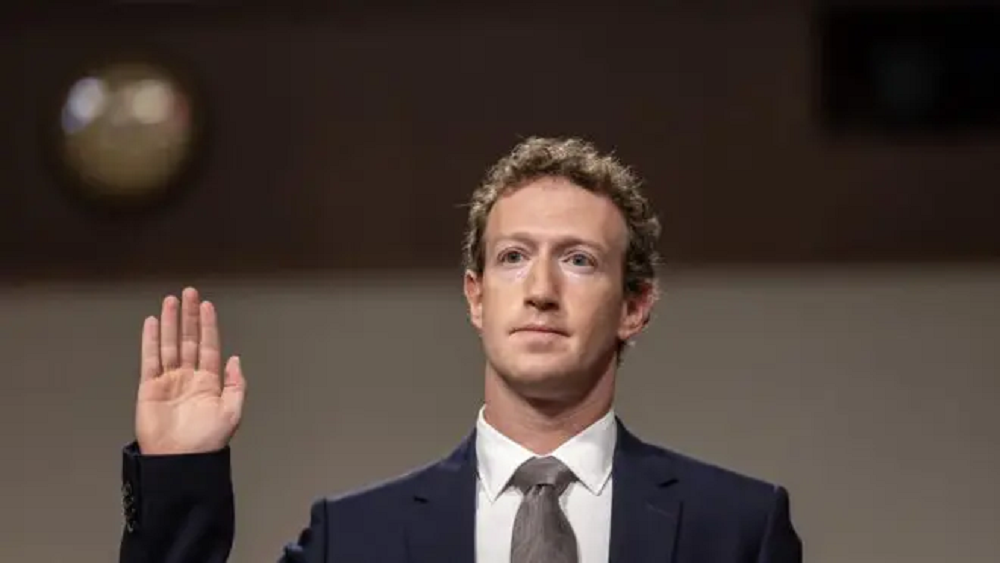 Mark Zuckerberg sério, levantando a mão direita