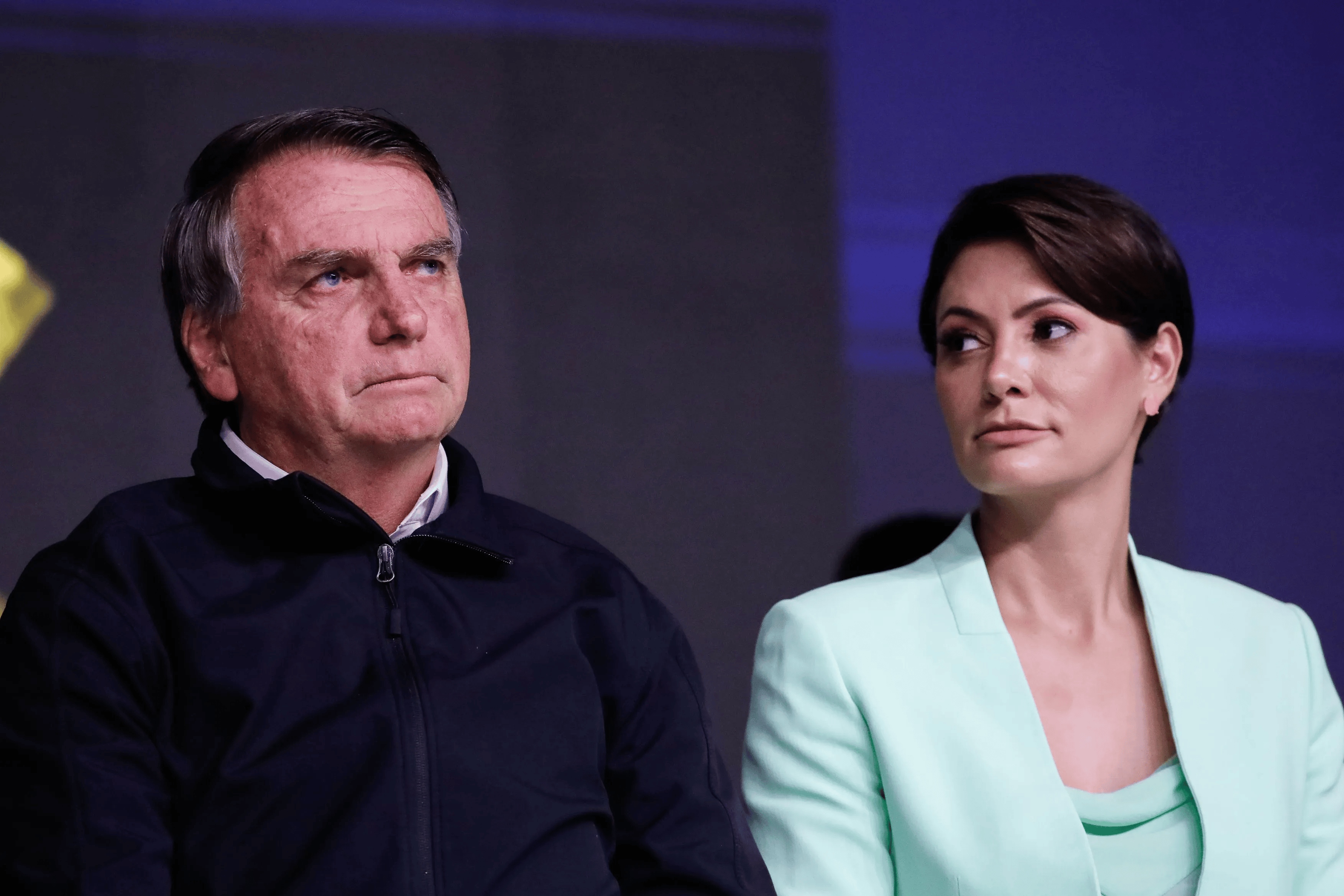 Jair Bolsonaro e Michelle sentados lado a lado, sérios