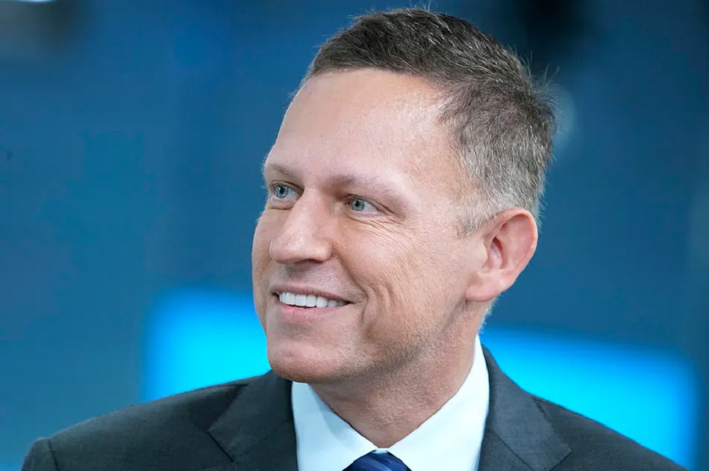 O empresário Peter Thiel, fundador do PayPal, olhando para o lado e rindo