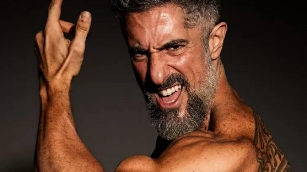 Marcos Mion sem camisa, fazendo careta e mostrando braço