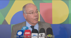 O ministro das Relações Exteriores, Mauro Vieira, falando em microfones, sério, olhando para o lado