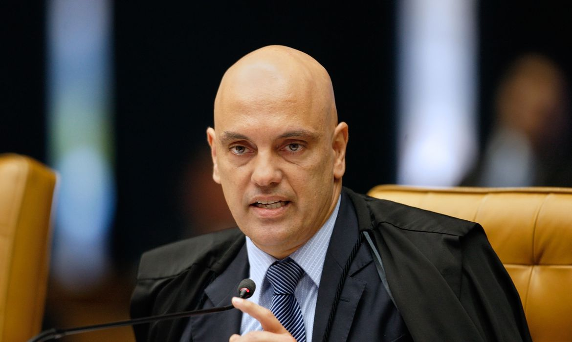 ministro Alexandre de Moraes falando com expressão séria em microfone e apontando