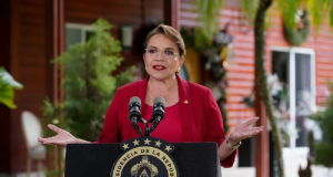 A presidenta de Honduras, Xiomara Castro, de roupa vermelha e cabelo preso, falando em microfone e gesticulando