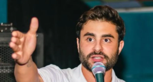 O vereador Pedro Rousseff (PT) de roupa branca, falando em microfone e apontando pra frente