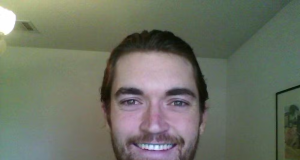 Ross Ulbricht, criador do site Silk Road, sorrindo para a câmera, em local fechado, de roupa xadrez