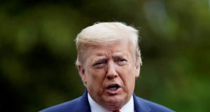 O presidente Donald Trump falando, sério, de terno e gravata