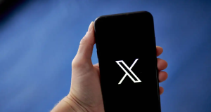 Mão segurando celular com a logo do X no fundo