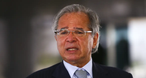 ex-ministro da Economia, Paulo Guedes, falando, de óculos, com expressão de insatisfação
