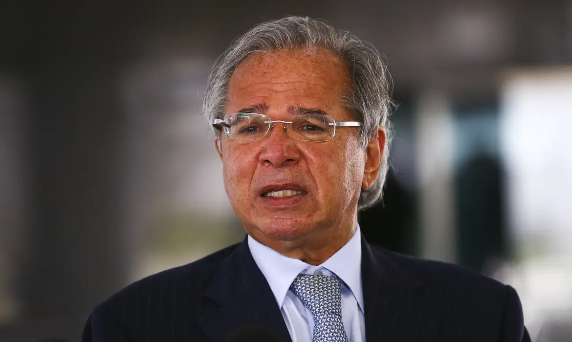 ex-ministro da Economia, Paulo Guedes, falando, de óculos, com expressão de insatisfação