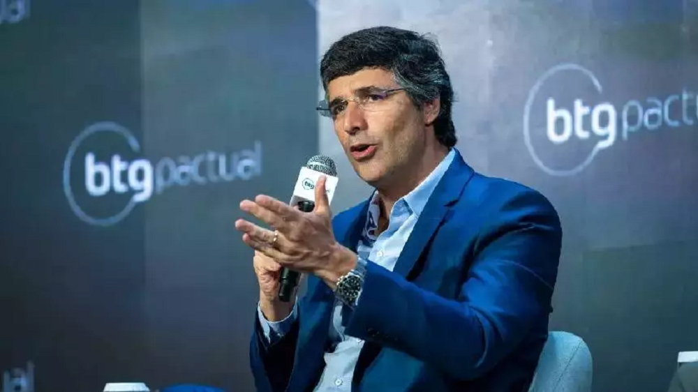 O banqueiro André Esteves, do BTG Pactual, falando em microfone e gesticulando