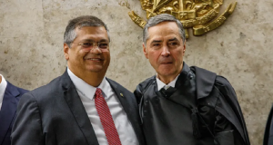 O presidente do Supremo Tribunal Federal (STF), Luís Roberto Barroso, e o ministro Flávio Dino posando lado a lado e sorrindo, sem olhar para foto