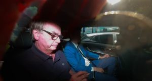 O ex-presidente Jair Bolsonaro (PL) dentro de carro, mexendo no celular, de roupa escura