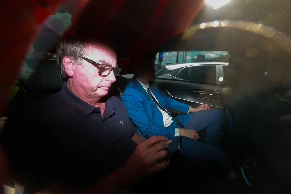 O ex-presidente Jair Bolsonaro (PL) dentro de carro, mexendo no celular, de roupa escura
