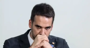Eduardo Leite sério, com mãos unidas na frente da boca