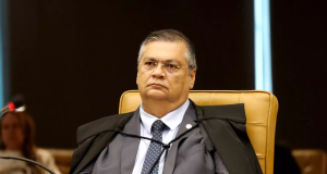 Flávio Dino sério, com expressão pensativa, sem olhar para a câmera