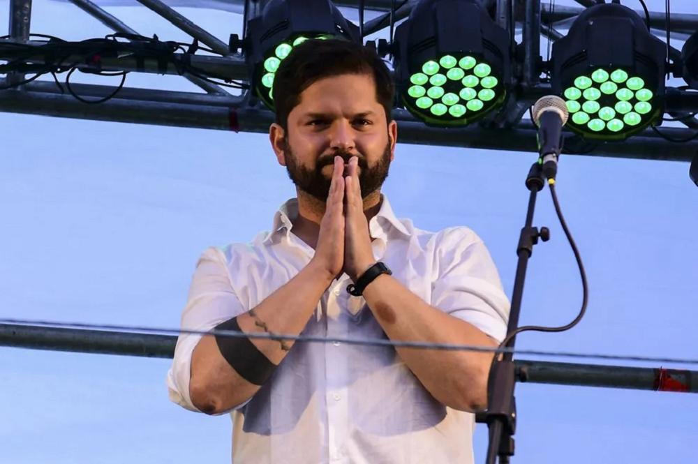 Gabriel Boric com as mãos unidas em sinal de agradecimento, sério