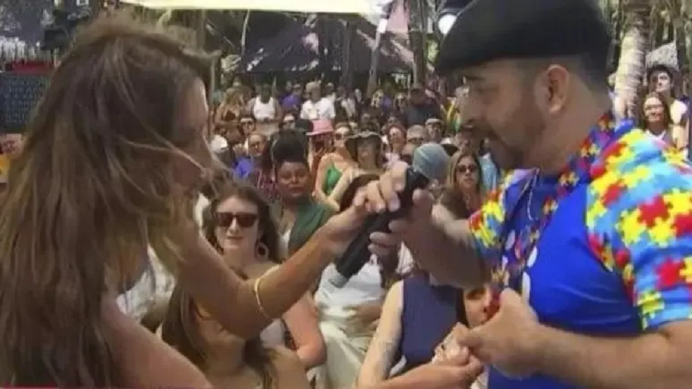 Patrícia Poeta de cabelo solto, abaixada, conversando com homem