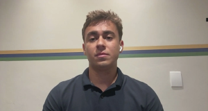 deputado federal Nikolas Ferreira (PL) de camisa polo preta olhando para a câmera, sério, com fone de ouvido branco sem fio