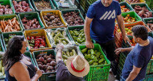 Pessoas próximas de prateleiras de verduras e legumes em supermercado