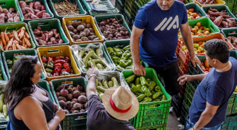 Pessoas próximas de prateleiras de verduras e legumes em supermercado