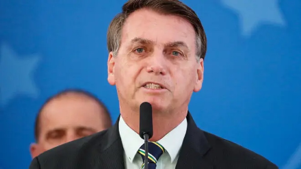 ex-presidente Jair Bolsonaro falando em microfone com cara de choro