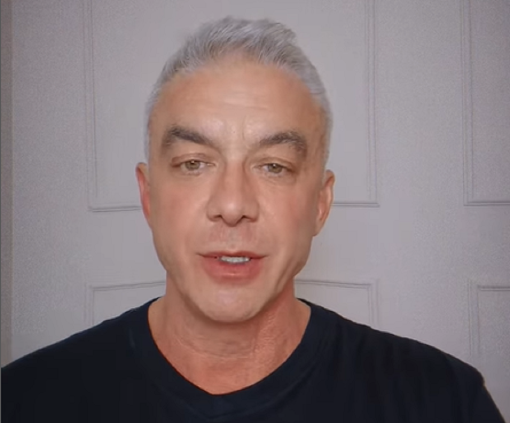 Alexandre Correa de camiseta preta, sério, falando para a câmera