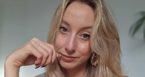 A britânica Abi Feltham fazendo carão para foto, em close, de cabelo solto e regata cinza