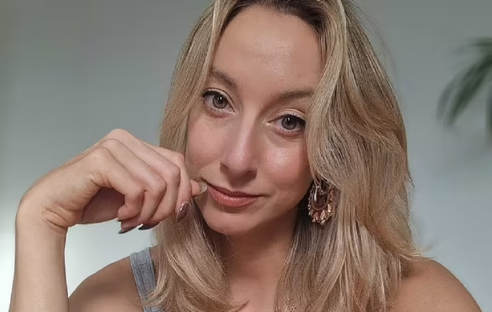A britânica Abi Feltham fazendo carão para foto, em close, de cabelo solto e regata cinza