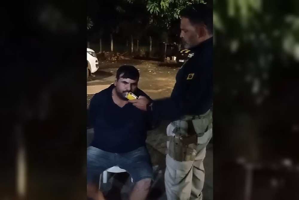 caminhoneiro Márcio Pinheiro Saldanha no centro de foto, fazendo teste do bafômetro