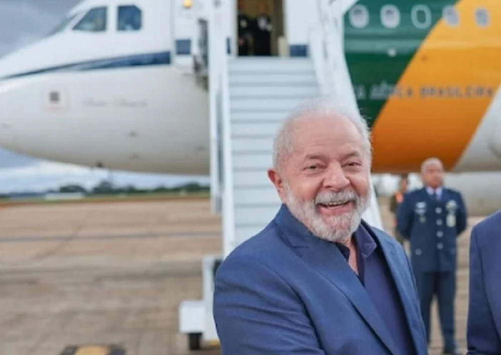 Lula sorrindo perto de avião, ele em primeiro plano