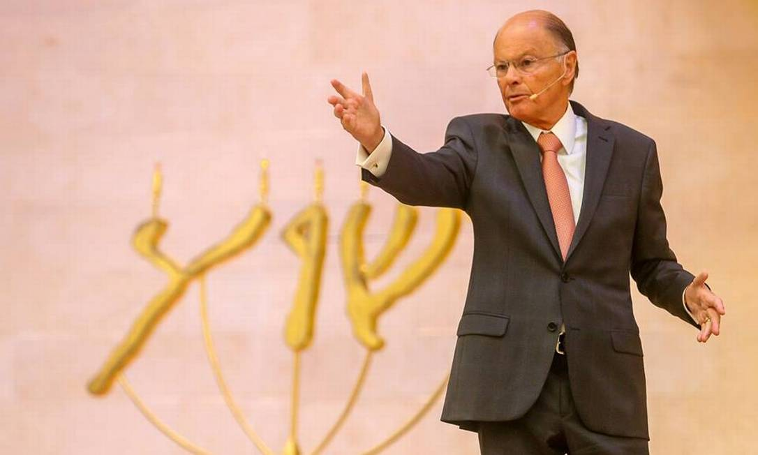 Edir Macedo, fundador da Igreja Universal, sério, falando e apontando pra frente, de terno e gravata, sem olhar para a câmera