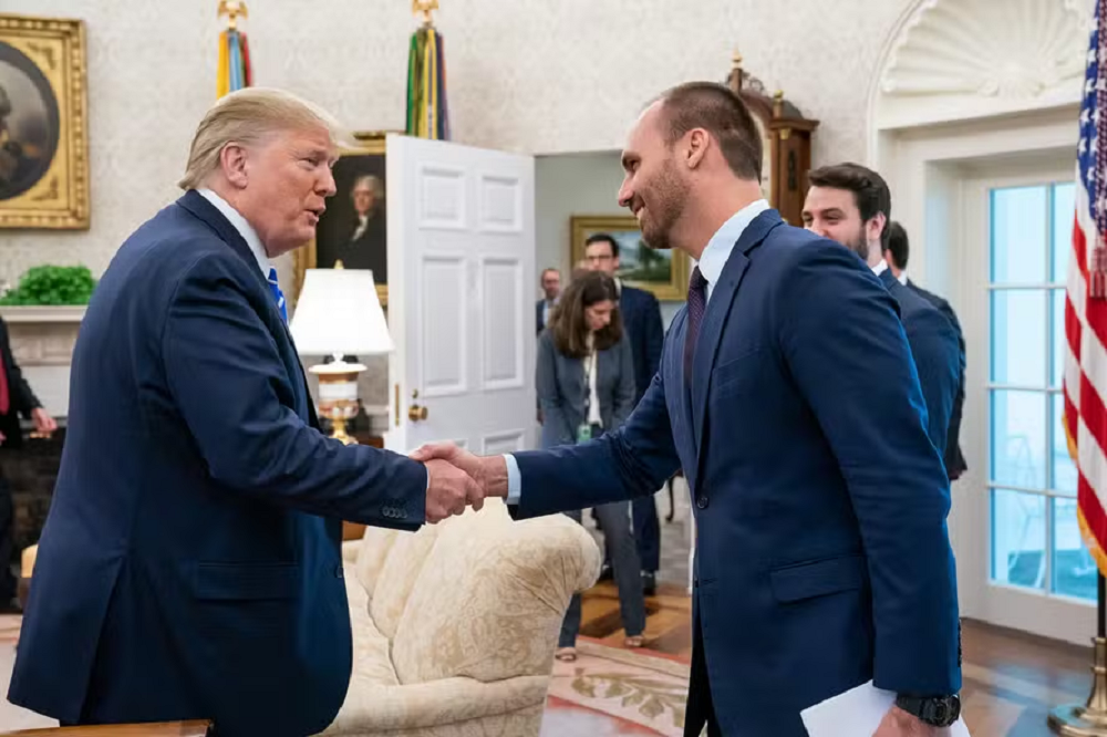 Donald Trump e Eduardo Bolsonaro (PL) em aperto de mãos