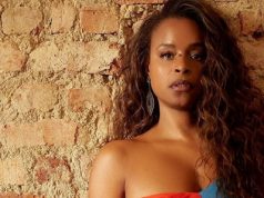 atriz Roberta Rodrigues séria, de cabelo solto e roupa colorida, posando encostada em parede, no canto direito de foto