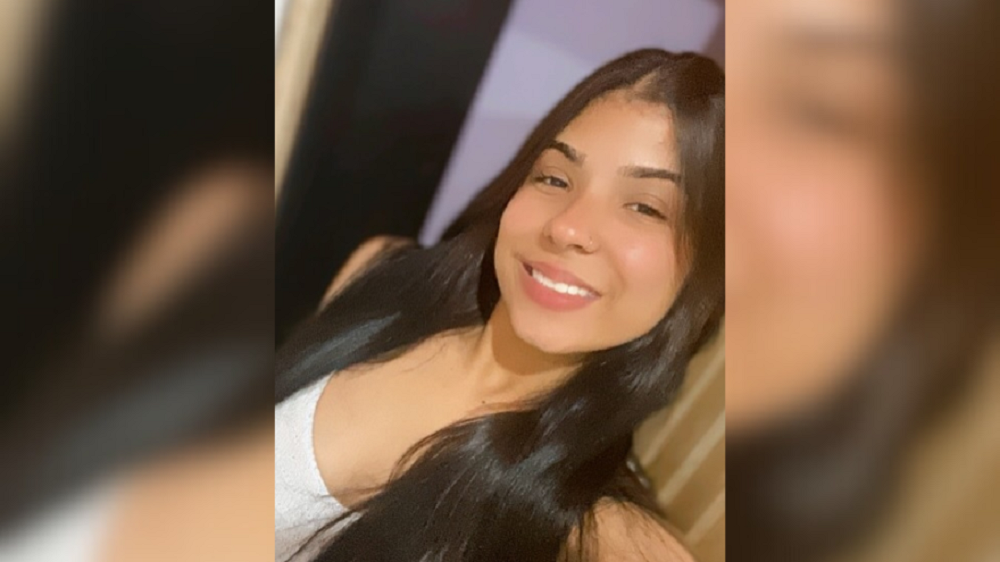 Vitória Regina de Sousa no centro de montagem, com roupa branca e cabelo solto, sorrindo para foto