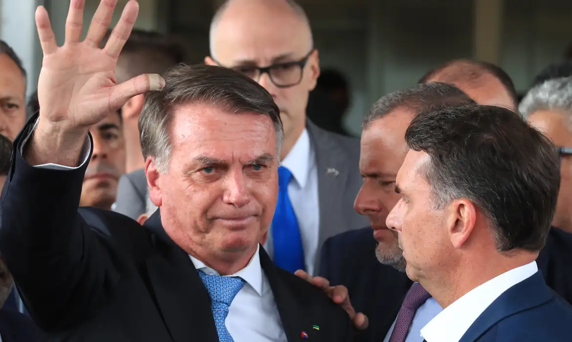Jair Bolsonaro sério, cercado, acenando