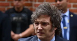 Javier Milei com expressão confusa, olhando para o lado, vestindo terno e gravata